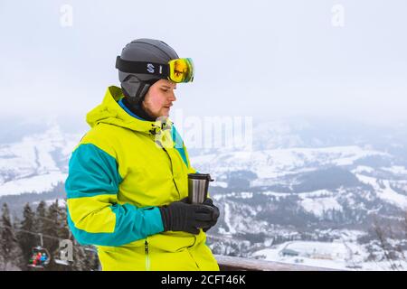 homme gagne un ensemble de snowboard en buvant du thé d'échauffement de rechargeable tasse Banque D'Images