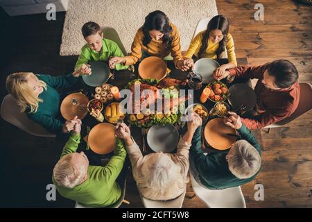 Au-dessus de la vue de haut angle de belle belle et paisible heureusement la famille assis autour de la table servie priant dieu en disant grâce apprécier repas domestique à Banque D'Images