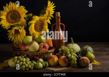 Encore la vie avec des tournesols de fruits, de raisins et de vin sur un fond noir avec l'espace de copie. Thanksgiving et récolte. Banque D'Images