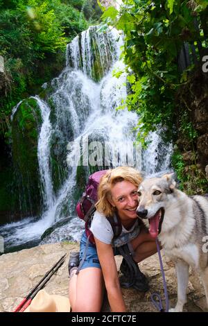 Randonneur jeune femme mature avec un chien et une cascade. Banque D'Images