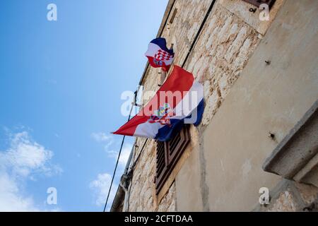 Deux drapeaux croates balançant dans le vent, pendu des fenêtres de la maison traditionnelle en pierre dalmate dans la ville de Stari Grad sur l'île de Hvar Banque D'Images