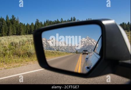 Vue sur le parc national de Grand Teton dans le Rétroviseur intérieur d'une voiture conduite dans le Wyoming Banque D'Images