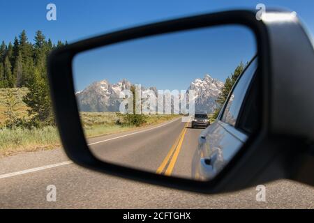 Vue sur le parc national de Grand Teton dans le Rétroviseur intérieur d'une voiture conduite dans le Wyoming Banque D'Images