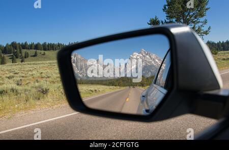 Vue sur le parc national de Grand Teton dans le Rétroviseur intérieur d'une voiture conduite dans le Wyoming Banque D'Images