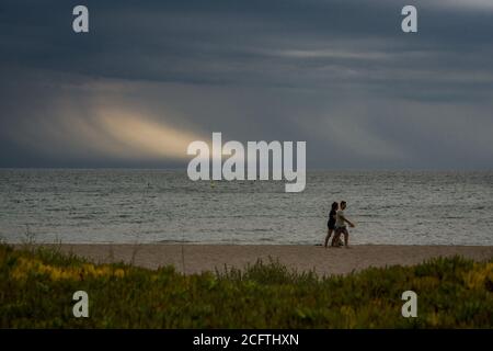 Sant Pere Pescador, province de Gérone, Espagne. 6 septembre 2020 - UN couple marche à la plage de Sant Pere Pescador, au nord de l'Espagne, comme les colonnes de pluie tombent à l'horizon. La fin des vacances d'été a été avec le temps orageux. Credit: Jordi Boixareu/Alamy Live News Banque D'Images