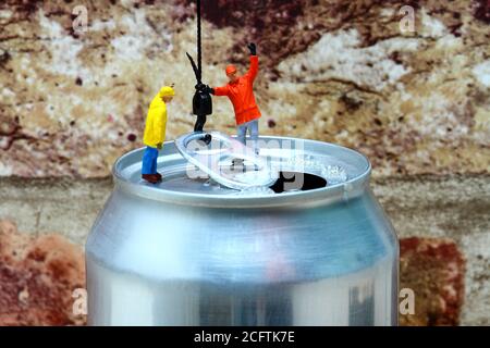 Image conceptuelle de la figure miniature des ouvriers qui fixent un crochet de grue à l'anneau tirer d'une boîte de boissons gazeuses en aluminium Banque D'Images