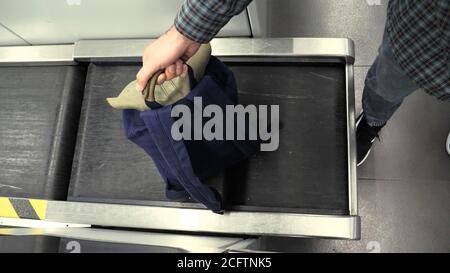 Main de l'homme avec un sac à dos sur le système de transport de bagages au bureau d'enregistrement à l'aéroport. Retour bleu au comptoir d'enregistrement de l'aéroport, mesurant le Banque D'Images