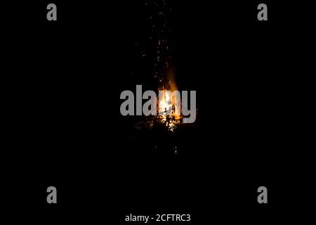 Feu sur fond sombre. Feu de bois de chauffage de près. Étincelles brûlantes brûlantes en gros plan, schémas d'incendie. Rouge et orange lueur infernale de feu dans la da Banque D'Images