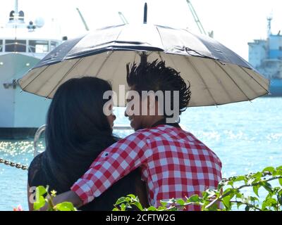 De jeunes amoureux heureux sur les rives de l'océan Indien, île Maurice. Une fille mauricienne et un gars sous parapluie. Saint-Valentin à Maurice. Date romantique. Banque D'Images