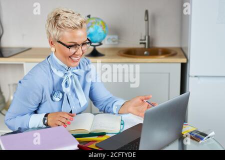 blonde blanche jeune enseignante enseignant d'école utilisant la webcam à la maison, concept d'enseignement virtuel, donnant la leçon en ligne de classe à distance par zoom conférence téléphonique Banque D'Images