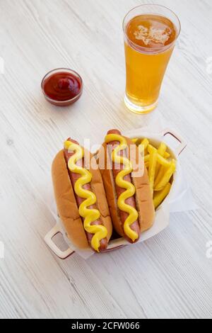 Hot Dog à la moutarde maison avec frites sur fond de bois blanc, vue en grand angle. Banque D'Images