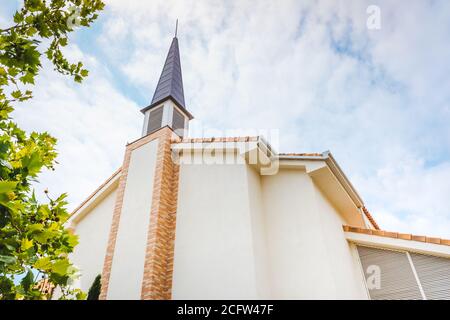 Façade d'une église évangélique avec des murs blancs lisses et un fond ciel nuageux. Banque D'Images