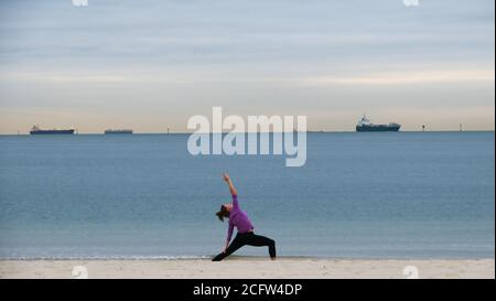 Melbourne Australie. Scènes de la vie quotidienne à Melbourne en Australie. Une femme faisant du yoga sur la plage de Port Phillip Bay. Banque D'Images