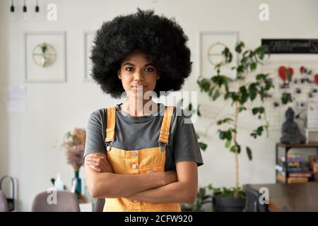 Une femme africaine confiante avec des cheveux afro regarde des stands d'appareil photo dans un café, portrait. Banque D'Images