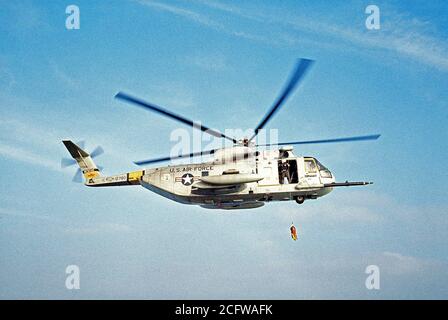 1977 - Une mer-air vue côté droit d'un HH-3 Jolly Green Giant de la descente d'une ligne de sauvetage par hélicoptère au cours d'une mission de sauvetage pratique sur la côte californienne. L'hélicoptère est affecté à la 129e groupe de sauvetage et de récupération de l'aérospatiale de l'Air National Guard. Banque D'Images