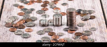 Des piles de quartiers sur une ancienne table en bois au milieu de dispersion concept de croissance des pièces / investissements Banque D'Images