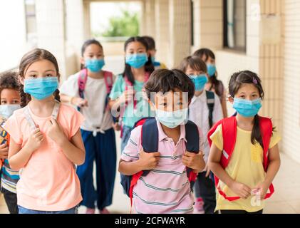 les enfants portant un masque médical pour le visage de retour à l'école après le covid-19 quarantaine Banque D'Images