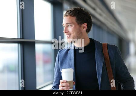 Un homme d'affaires heureux qui va travailler en buvant du café - style de vie de voyage ou trajet de la vie urbaine matin. Jeune homme professionnel près de la fenêtre dans le bureau Banque D'Images