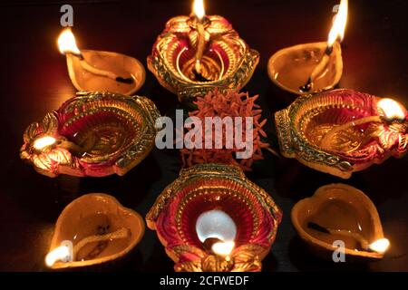 Lampes à huile Diwali colorées, lampes à huile Deepavali illuminées en belle formation avec des fleurs au milieu. Banque D'Images