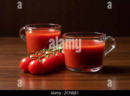 Jus de tomate et tomates fraîches placées sur le fond d'un arbre, photographiées sur le côté Banque D'Images