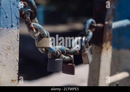 Plusieurs cadenas pendent d'une ancienne chaîne. Cadenas de mariage enchaînés au pont de la ville. Symbole de l'amour et de la tradition de mariage ancienne. Vieux rouillé chéri l Banque D'Images