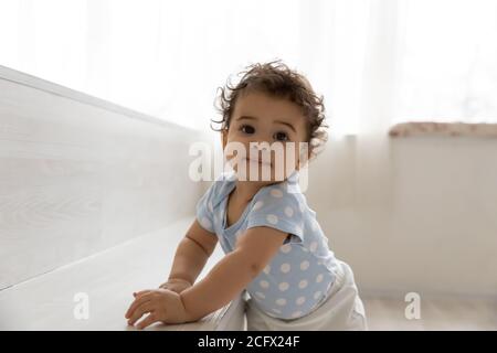 Adorable petit enfant africain s'appuyant sur des meubles, faisant des premiers pas. Banque D'Images