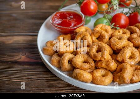 Tortellini fait à la main avec des tomates et des verts de thym sur une plaque blanche est appelé taralli. Taralli dans les boulangeries italiennes dans le sud de l'Italie sur un bois Banque D'Images