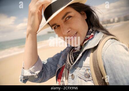 Portrait d'une femme de 40 ans aux cheveux foncés, portant un chapeau et se tenant sur la plage Banque D'Images