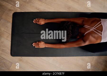 Vue en grand angle du dos de la femme pendant l'exercice et la flexion vers l'avant à la maison pendant le verrouillage Banque D'Images