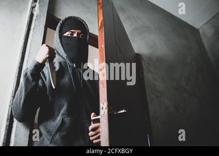 Le voleur est titulaire d'un couteau pour ouvrir la porte de la maison pour vol qualifié. Banque D'Images