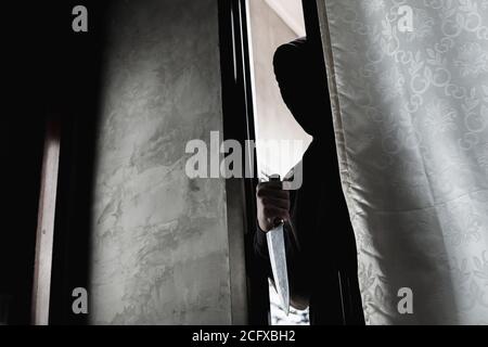 Le voleur tient un couteau pour ouvrir la porte de la maison pour le cambriolage un visage de couteau ne peut pas être vu. Banque D'Images