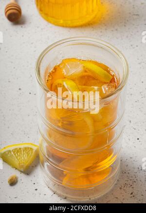 mise au point sélective, un grand verre de thé glacé au citron avec un pot de miel sur un fond clair Banque D'Images