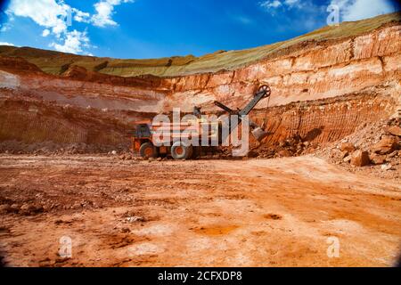 Exploitation et transport du minerai d'aluminium. Argile à bauxite. La pelle hydraulique charge le minerai sur le tombereau de carrière Hitachi. Banque D'Images