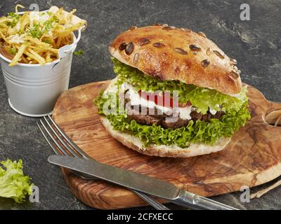 Hamburger rustique fait maison avec pommes de terre frites Banque D'Images