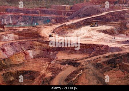 Carrière de minerai d'aluminium de couleur. Bauxite à ciel ouvert (coupe ouverte) pour l'exploitation minière. Marches de carrière. Vider les chenilles (tombereaux de carrière) et la pelle hydraulique. Banque D'Images