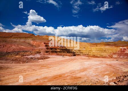 Carrière de minerai d'aluminium. Mine de bauxite à coupe ouverte. Étapes de carrière de différentes couleurs de minéraux. Sur le ciel bleu profond avec des nuages blancs. Banque D'Images