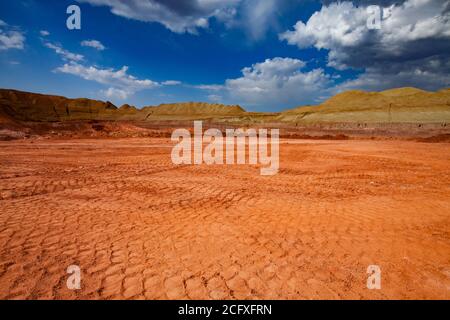 Carrière de minerai d'aluminium. Mine de bauxite à coupe ouverte. Le camion traîne sur le sol. Herbe verte sur les tas. Ciel bleu avec nuages. Vue panoramique. Banque D'Images