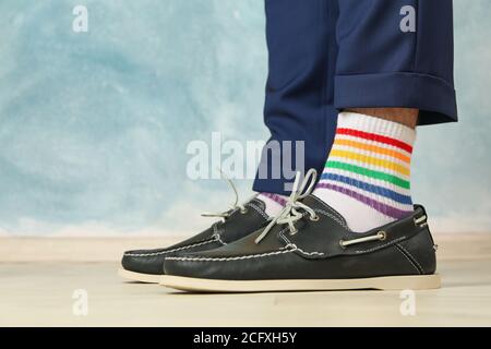 Homme dans un pantalon bleu, des mocassins et des chaussettes LGBT sur fond bleu Banque D'Images
