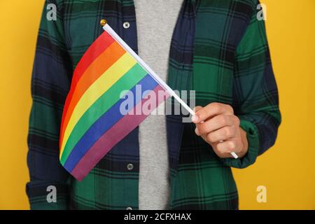 Homme porte le drapeau LGBT sur fond jaune Banque D'Images