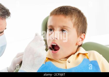 Le dentiste regarde l'enfant avec un miroir dans la bouche Banque D'Images