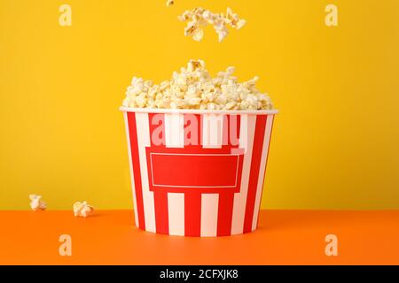 Seau en carton avec pop-corn savoureux sur fond jaune Banque D'Images