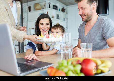 La famille et l'enfant célèbrent leur anniversaire avec un gâteau maison chat vidéo Banque D'Images