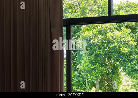 Rideau brun moderne dans la chambre fermée à mi-chemin au soleil brillent à travers le balcon du jardin extérieur arrière. Banque D'Images