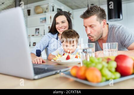 Père et enfant soufflent des bougies ensemble sur le gâteau d'anniversaire dans le chat vidéo Banque D'Images