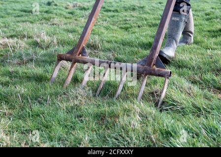 deux pieds aérant une pelouse d'herbe avec de larges pieds en métal fourré portant des bottes wellington. Banque D'Images