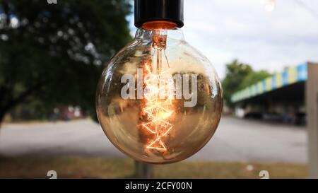 Les ampoules à incandescence Edison sont suspendues dans un style loft rétro. Décoration de la cafétéria en gros plan. Décoration de rue, lanternes claires, lumière chaleureuse. Flou artistique et flou artistique Banque D'Images