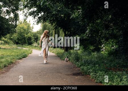 Une jeune femme dans un masque facial médical protecteur marche avec un chaton écossais droit dans le parc pendant la pandémie de covidvirus covid-19. Banque D'Images