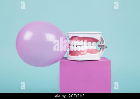 un modèle anatomique de dent en plastique pour apprendre à brosser les dents en tenant une boule de gomme à mâcher sur des cubes colorés. Humour et ambiance pop. Minimale Banque D'Images