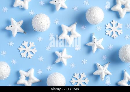 Composition de Noël. Motif composé de flocons de neige blancs, boules, étoiles, confetti sur fond bleu. Flat lay, vue de dessus. Banque D'Images