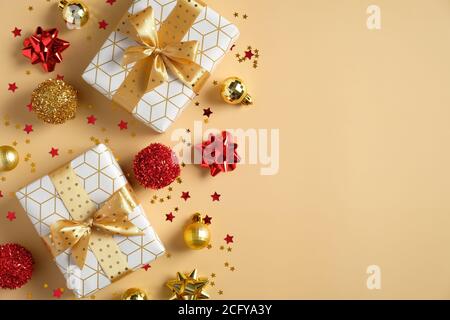 Composition de Noël. Boîtes-cadeaux avec boucles de ruban doré, décorations de boules de lecture et d'or, étoiles confetti sur fond jaune. Flat lay, vue de dessus, Banque D'Images